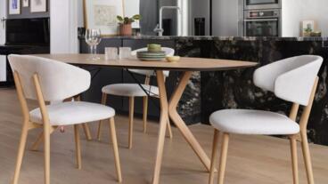 Moderne eettafel met licht houten stoelen en decoratieve servies in stijlvolle keuken