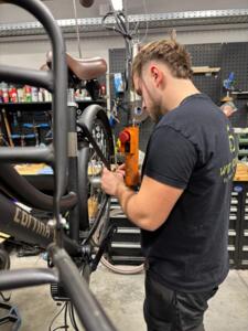 Fietsenmaker repareert elektrische fiets in werkplaats met gereedschap en onderdelen op achtergrond