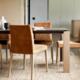 Moderne eetkamer met bruine fluwelen stoelen en een houten eettafel op een beige vloerkleed