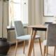 Lichte eetkamer met moderne stoelen en houten tafel naast groot raam en planten