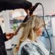 Kapster maakt zachte, glanzende waves in blond haar met een krultang in de salon van High Hair.