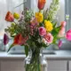 Kleurig boeket in doorzichtige vaas met tulpen en rozen.